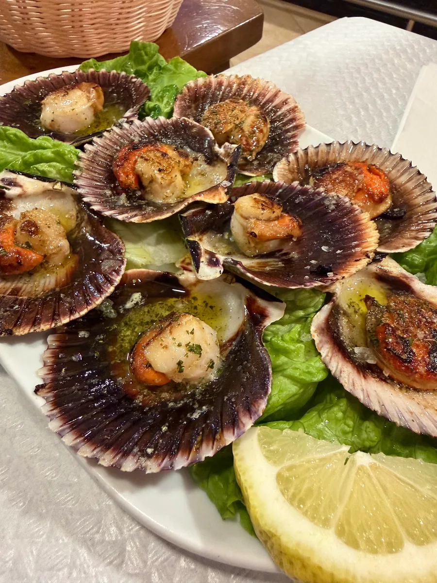 Fuente de zamburiñas a la plancha servidas en su concha, con aceite de ajo y perejil y sal en escamas