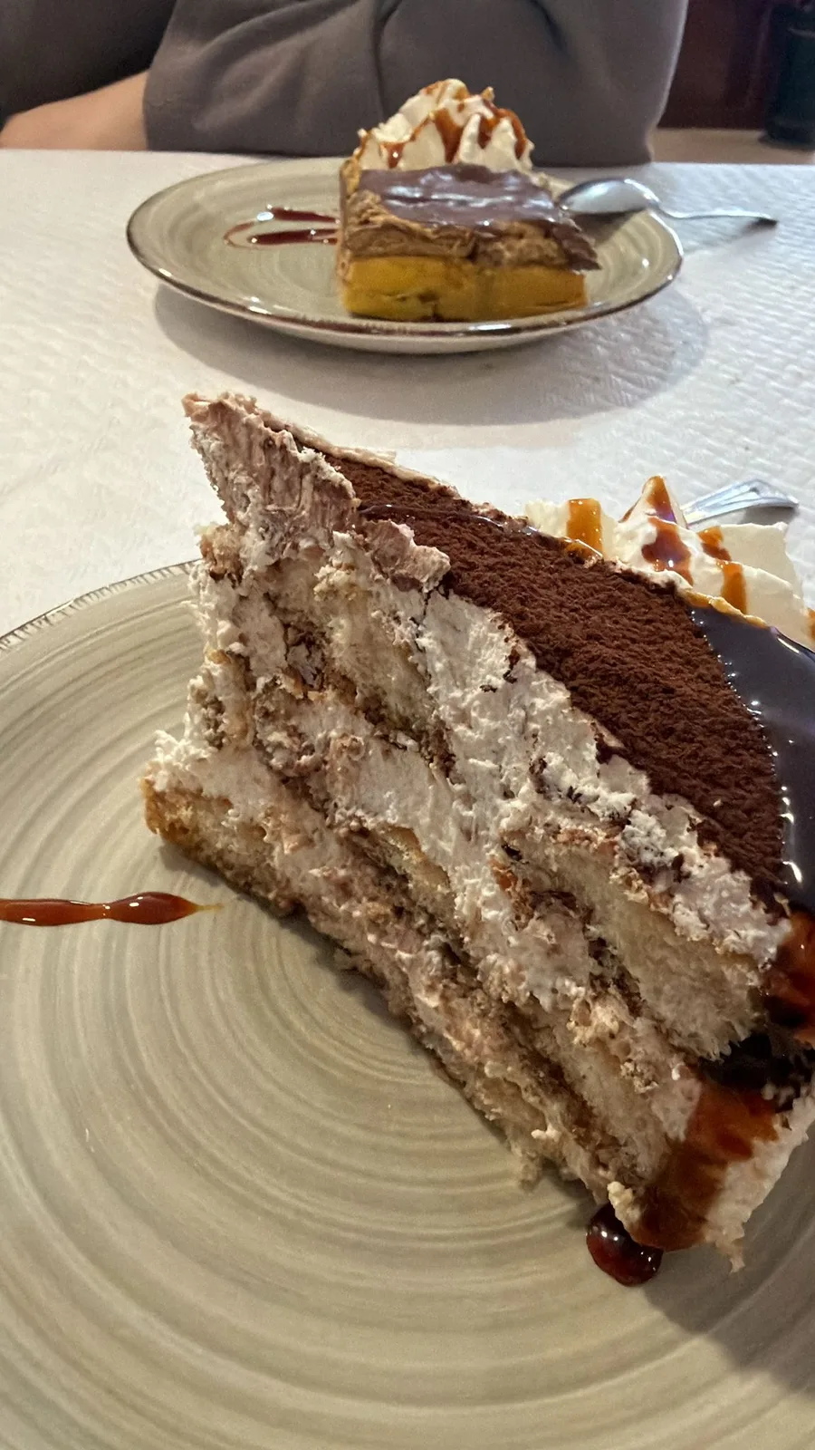 Ración de tarta casera por capas de nata y galleta, con cacao espolvoreado y cobertura de chocolate