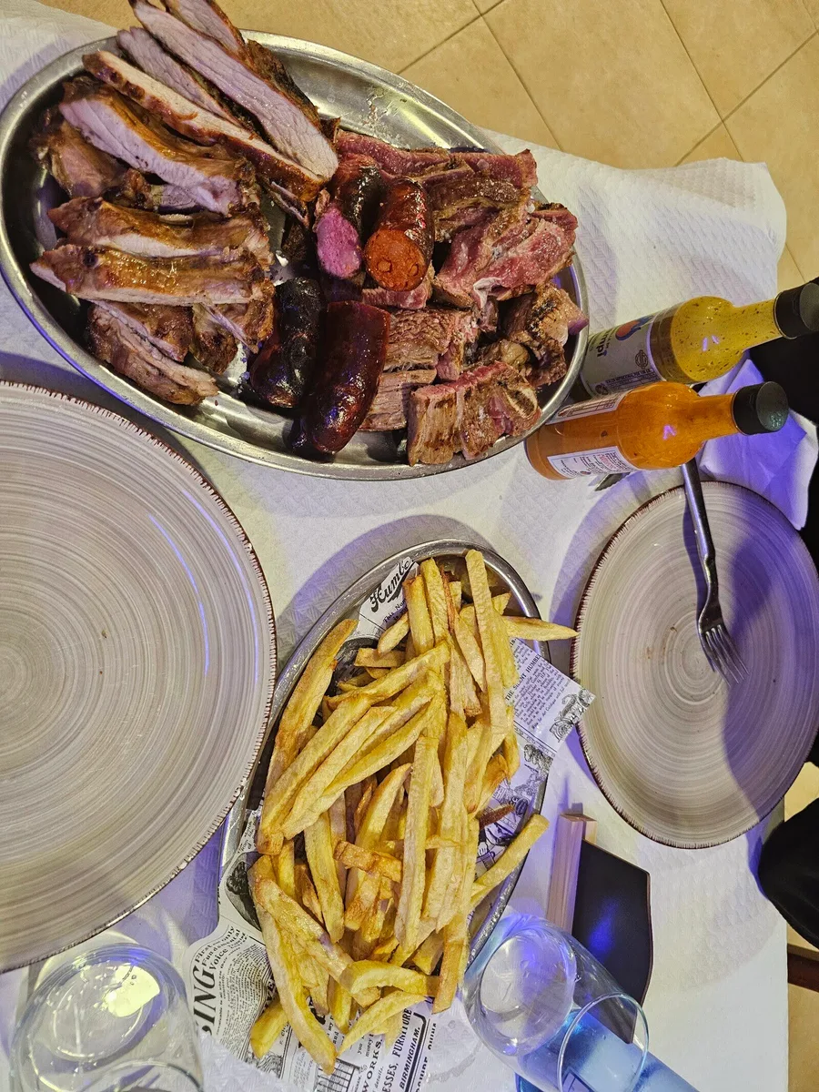 Fuente metálica de parrillada a la brasa con costillas, chorizo, morcilla y tiras de carne de cerdo